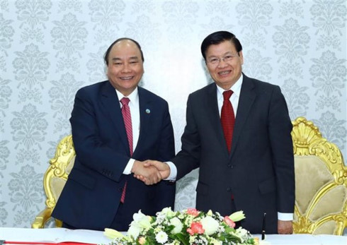 Prime Minister Nguyen Xuan Phuc (L) shakes hands with his Lao counterpart Thongloun Sisoulith at the inaugural ceremony of the Star Telecom's new headquarters